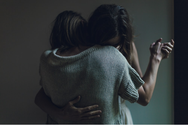Two women hugging each other for emotional support, a secondary trauma concept