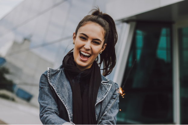 A woman smiling while holding a firecracker