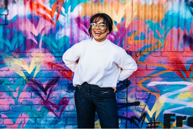 A woman smiling while standing in front of a multicolored wall