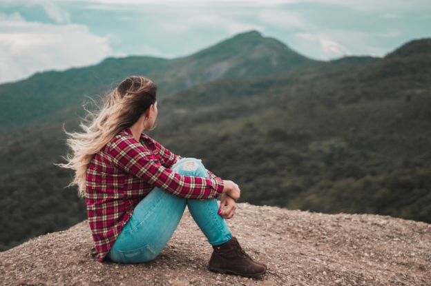 A woman sitting alone while overlooking a hill