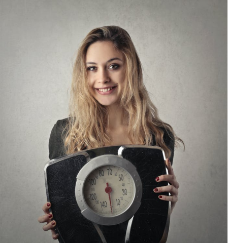 A smiling young woman holding a weight scale