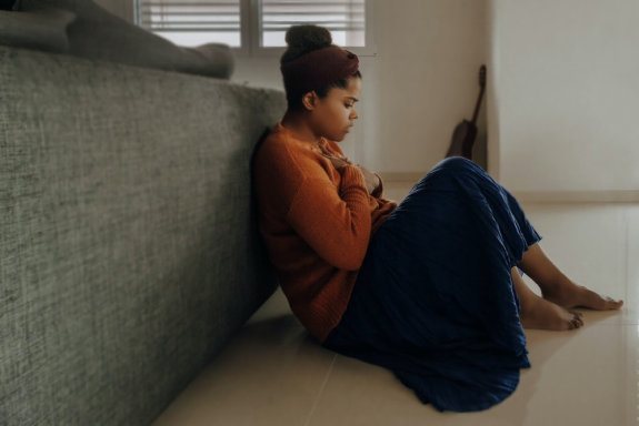 A woman sitting on her bedroom floor