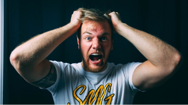 A Wide-Eyed Man, Mid-Scream, Pulling at his Hair with Both Hands