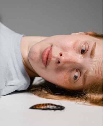 A Woman on Her Back and Facing a Cockroach, Looking Visibly Panicked