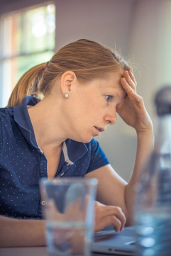 a woman in a blue shirt holding her head due to excessive worrying