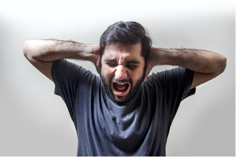 a man shouting while covering his ears