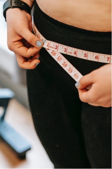 A woman measuring her waist with a measuring tape