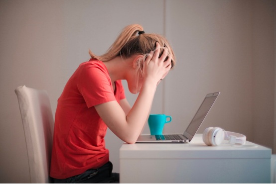 A woman struggles with anxiety while working and places her hands on her head