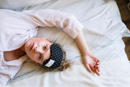 A person lays in bed staring right into the camera due to sleeplessness