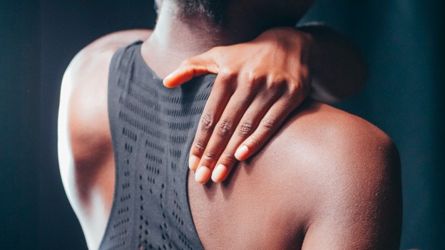 A woman grips her shoulder where she experiences chronic pain