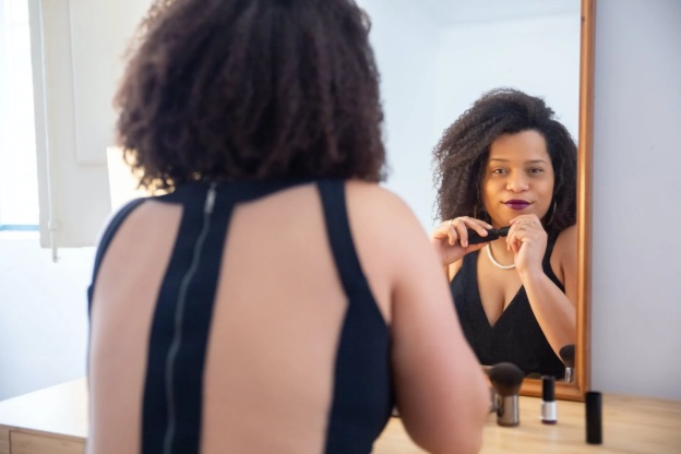 A woman looks at herself in the mirror, smiling with confidence