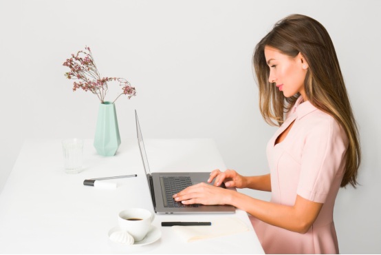 A woman works with concentration, using her laptop at her desk