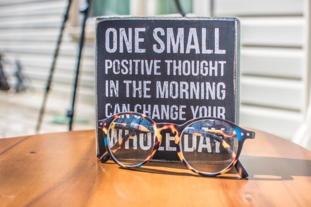 A daily affirmation board and a pair of glasses are placed on a table