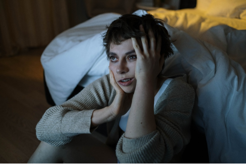 A person sitting against a white sheet looking sleep deprived