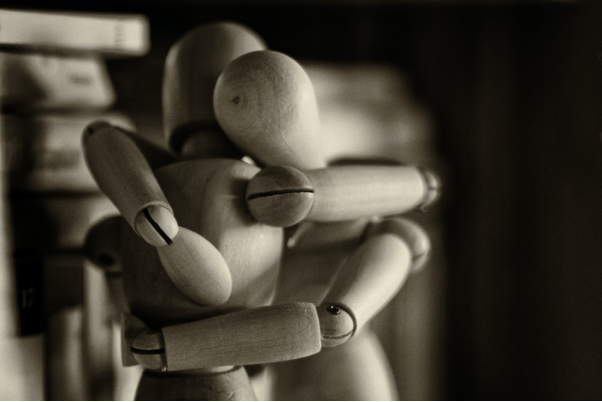 two wooden dummy hugging figures