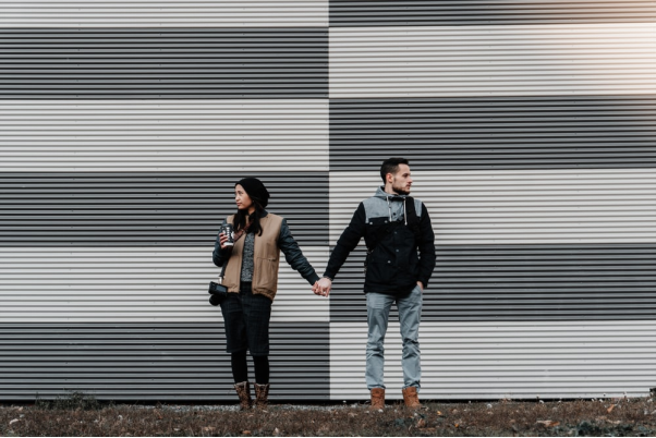 Man and woman holding hands while looking away