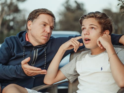 A teenager covering his ears as a man tries to talk to him