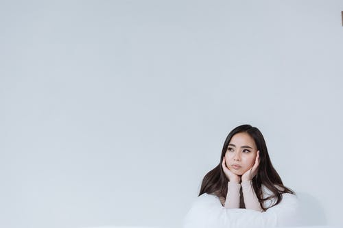 a woman leaning on white linen while holding her face