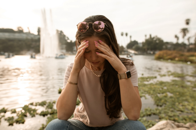 A person sitting outdoors with their head in their hands