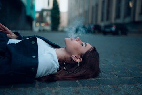 a woman smoking while lying on the street