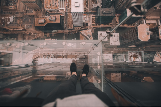 A person standing on a glass floor of a tall building