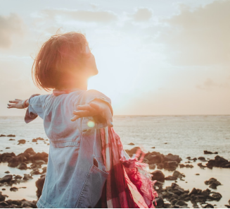 A person standing on a shore with their arms outstretched