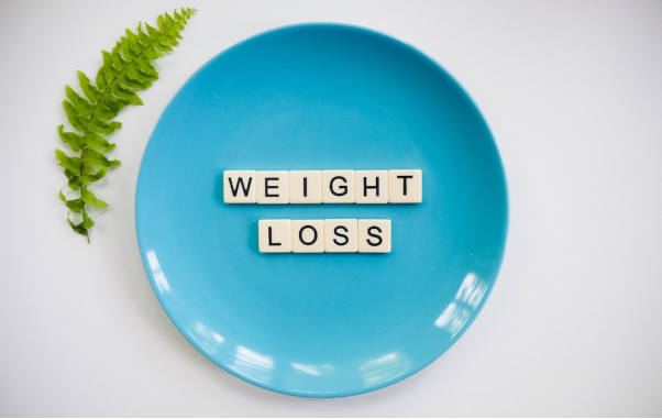A blue plate with scrabble tiles spelling out “weight loss”