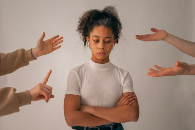 A Gen Z teen looks upset as people tell her off with their hands.