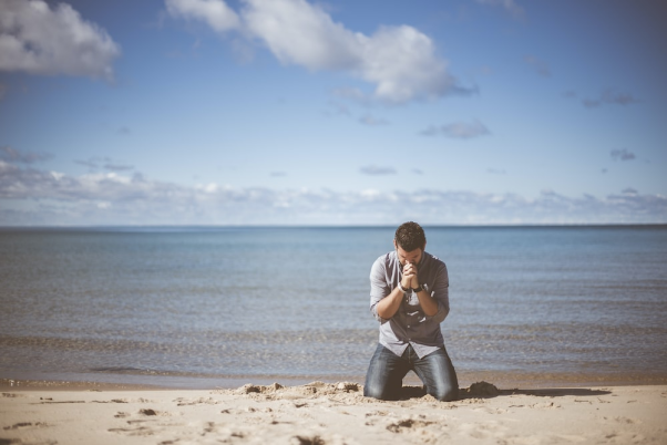 A person sitting on their knees on a beach