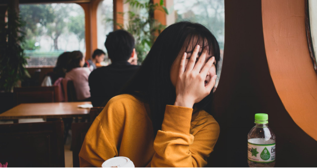 A woman hides her face out of shyness and self-consciousness